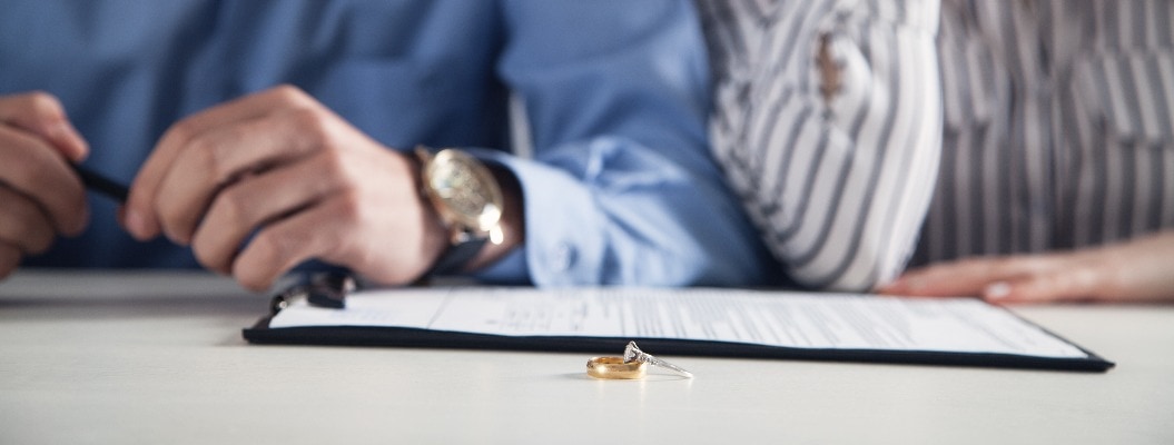 Ehepaar mit Scheidungsvertrag und Ring auf dem Schreibtisch